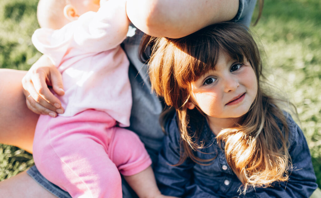 Close-up portrait of a little girl on her mother's lap breastfeeding her second baby. 