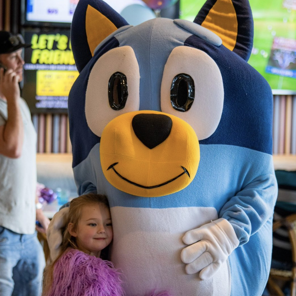 A young girl cuddles up to a Bluey mascot at The Macarthur Tavern.