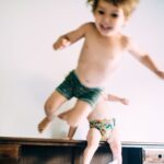 Two toddler dressed just in undies jumping on the bed