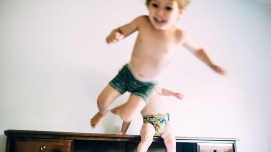 Two toddler dressed just in undies jumping on the bed