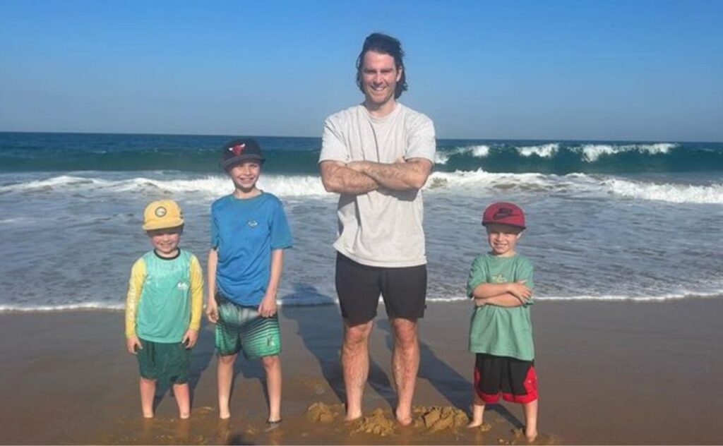 Jimmy Rees on the beach with his three children