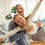 ather playing with his daughter, it's Christmas and they enjoy in time together. Father carrying daughter like plane.