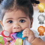 Close up of dark haired baby girl chewing on a colourful teething toy