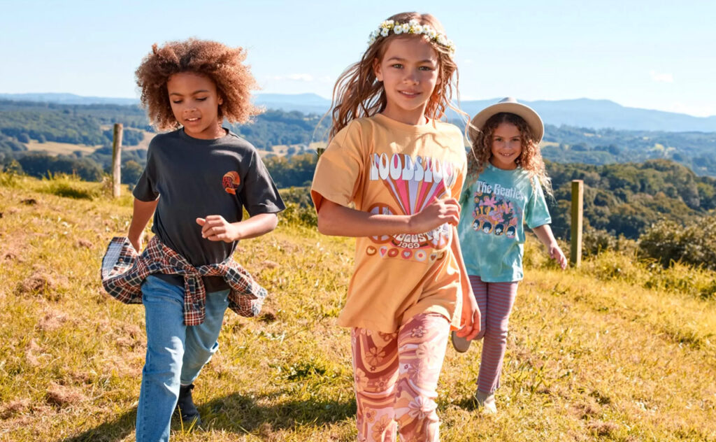 black friday sales - Three children frolicking in the grass wearing cotton on kids fashion