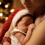 young mother posing with newborn under Christmas tree