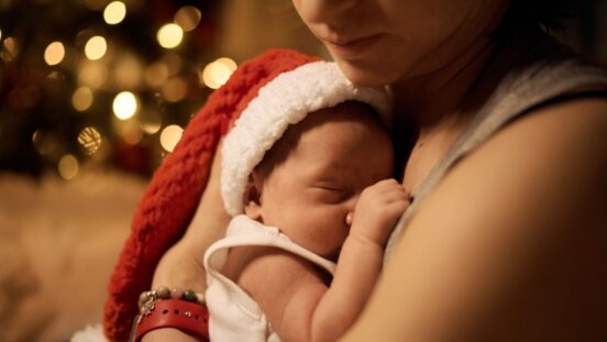 young mother posing with newborn under Christmas tree