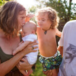 Real family in the garden on a hot day. Mother, father, toddler and baby.