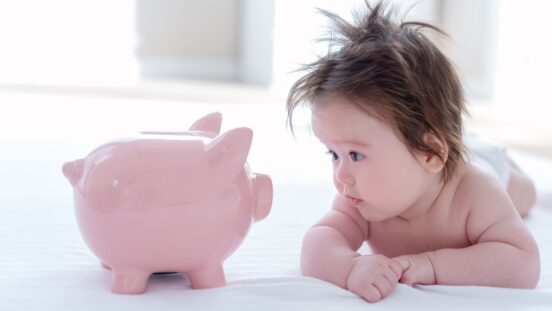 Wealthy baby names: baby boy looking at piggy bank