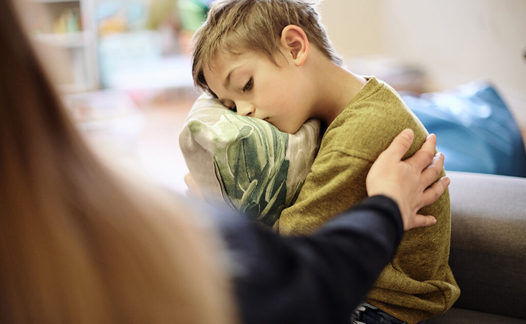 Autism, bullying and hand of mother with boy hugging pillow for comfort, compassion and empathy at home. Disability, abuse and mom with sad child suffering depression, adhd or mental health problem