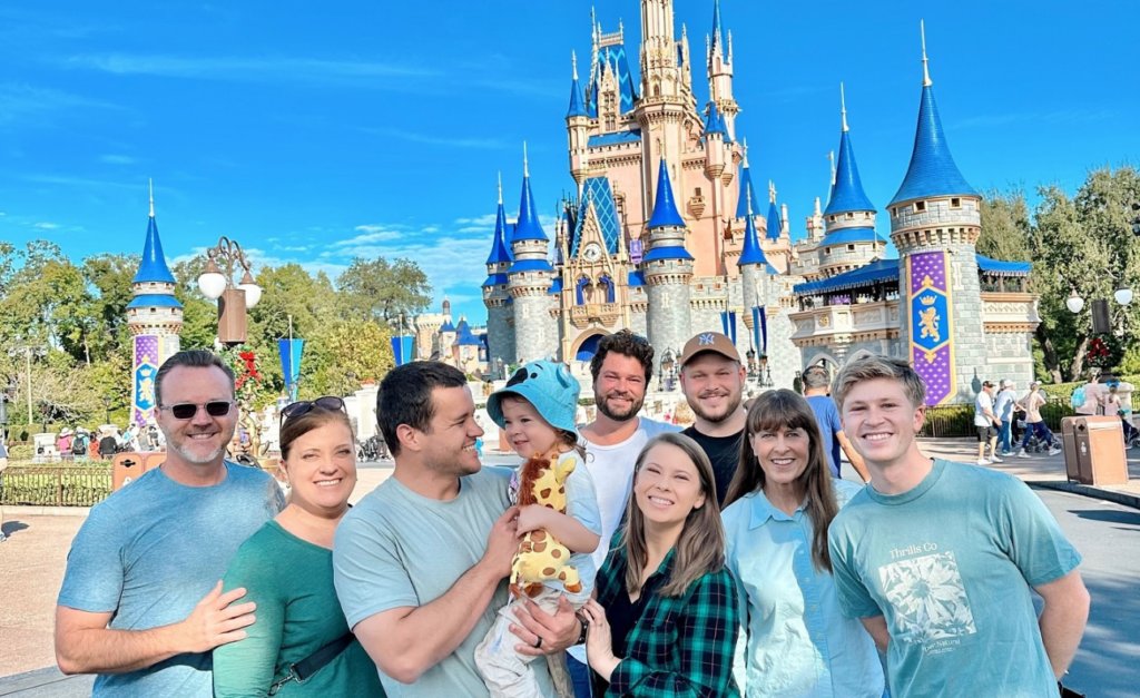 The Irwin and Powell families all dressed in blue in front of the Disney castle at Walt Disney World