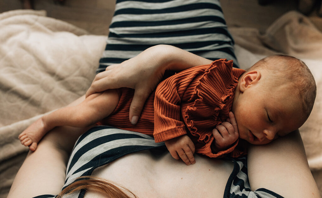 Close-up of a mother holding a newborn baby at home.