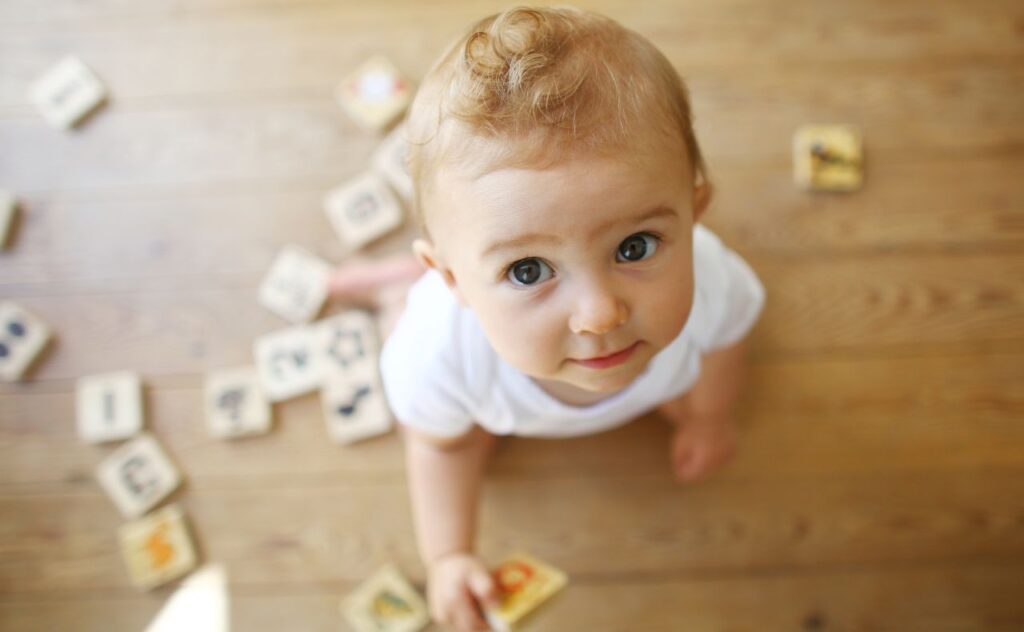 Baby playing with block and making eye contact.