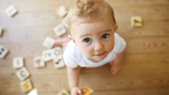 Baby playing with block and making eye contact.