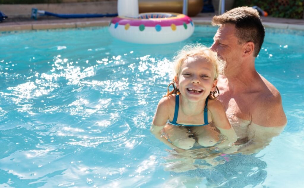 Girl swimming in pool with her dad