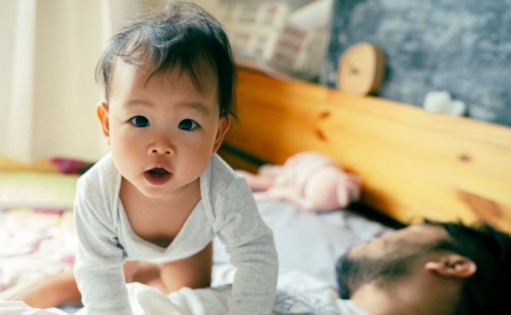 Asian baby awake parent asleep