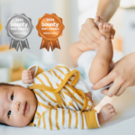 Cropped shot of young Asian mother changing her baby's nappy, with Gold, SIlver and Bronze Bounty Baby Awards badges on the image