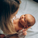 Mother making eye contact with alert newborn as she gets them dressed.