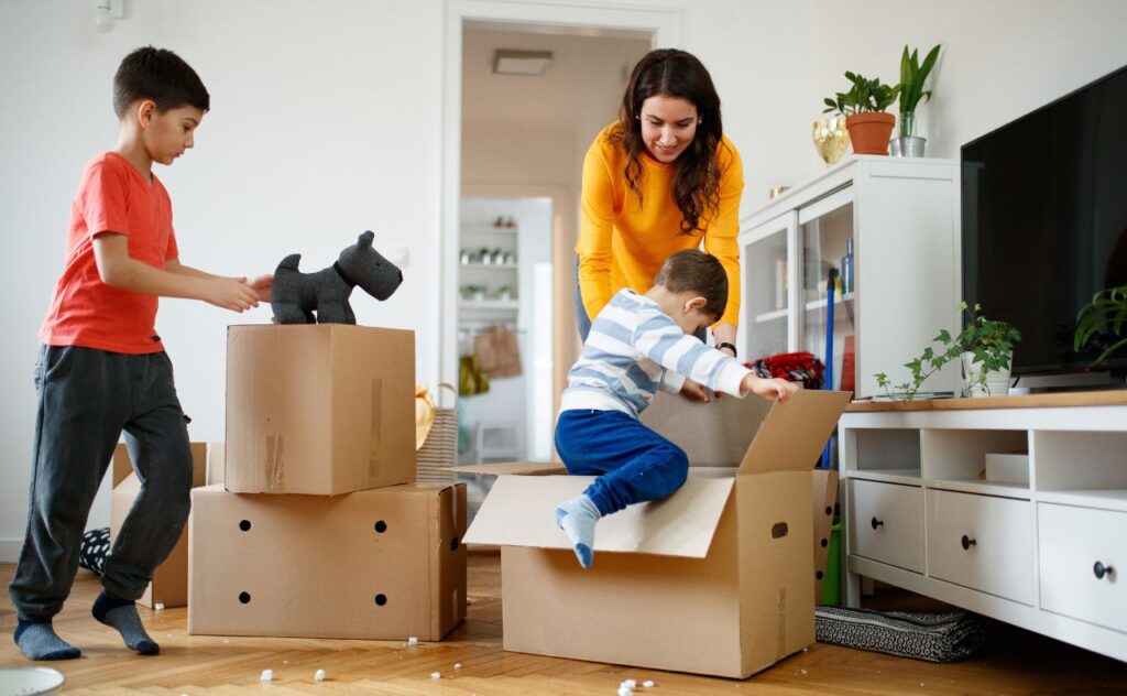 Mother smiling at toddler entering a box during packing for house move