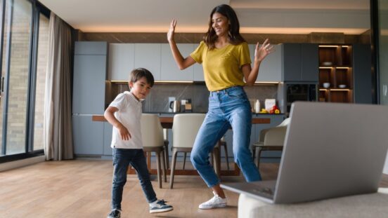 Babysitter/ young mum having fun dancing with child/ son at home