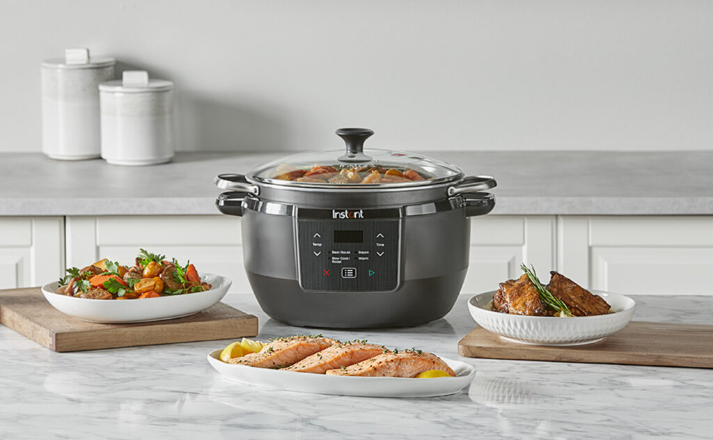 Instant™ Superior Slow Cooker 7.1L in kitchen setting with food on the bench nearby.