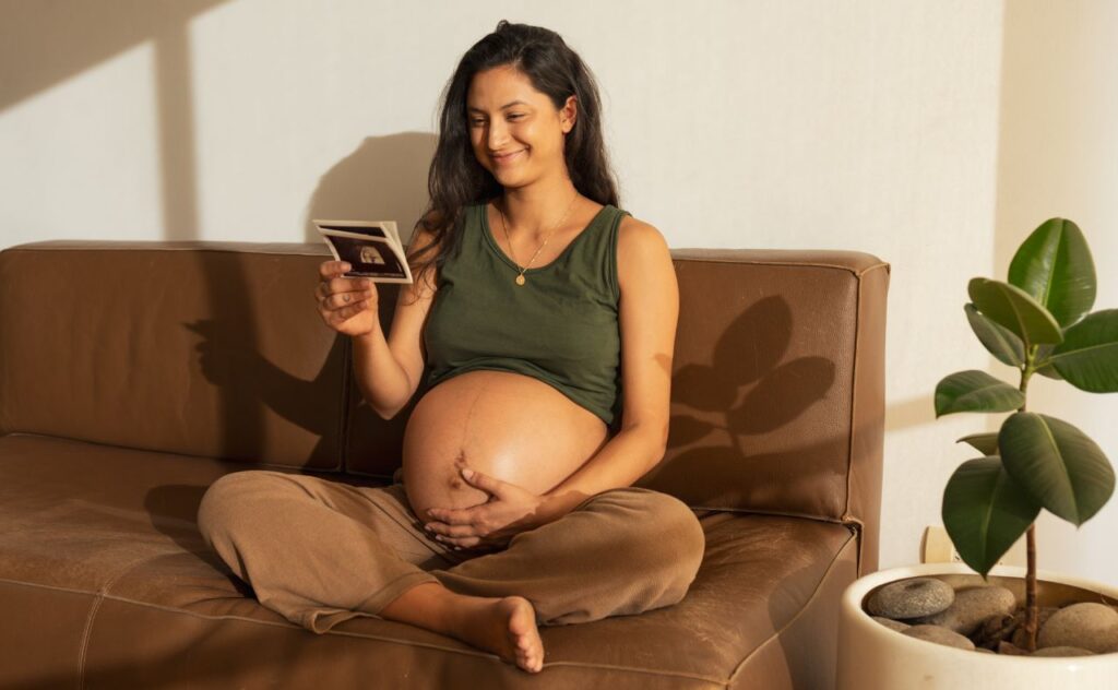 Happy pregnant woman looking at ultrasound scan at home