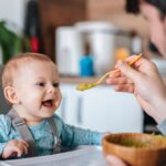 Father feeding his cute baby boy with vegetable puree.