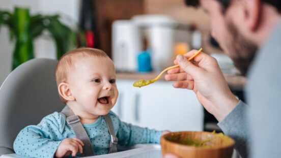 Father feeding his cute baby boy with vegetable puree.