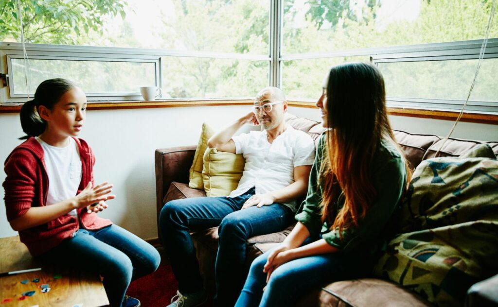 Father in discussion with daughters in living room