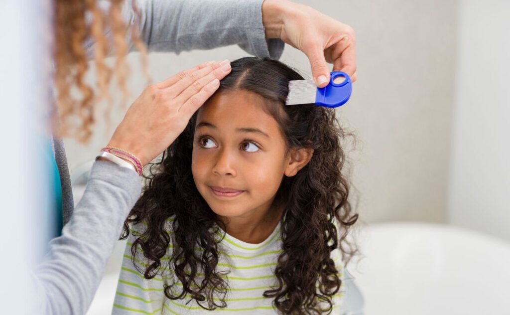 Mother using lice comb on daughters hair
