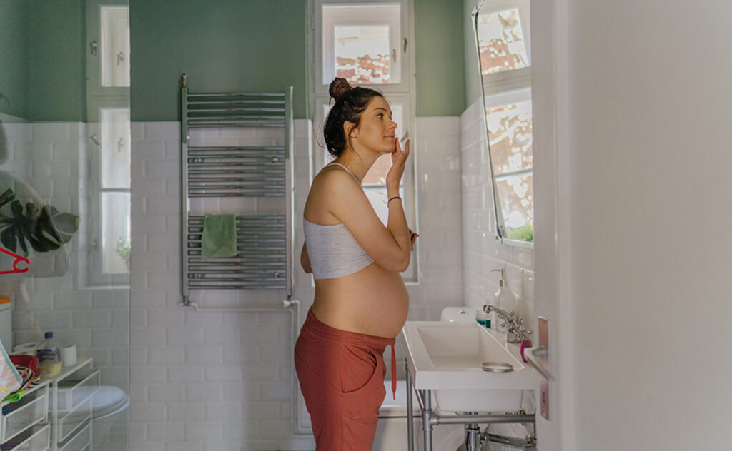 Caucasian pregnant woman looking at herself in the mirror