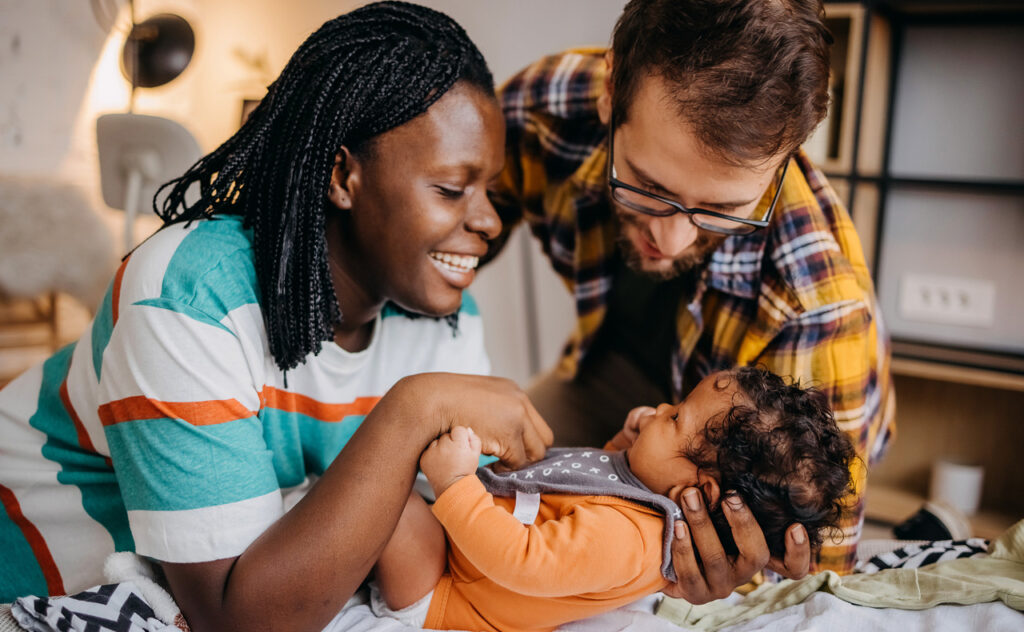 Young couple is playing with their newborn baby at home
