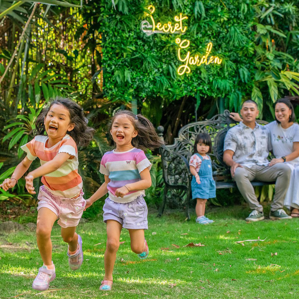 Family enjoy the green landscaped grounds of Cairns Harbourside Hotel