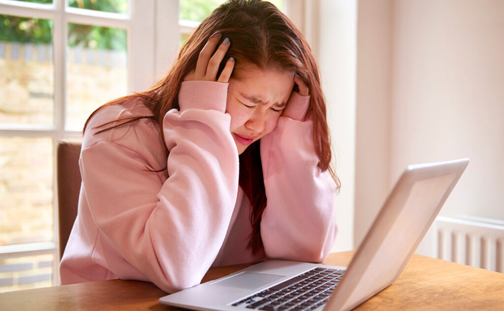 student girl with eyes closed and head in hands crying