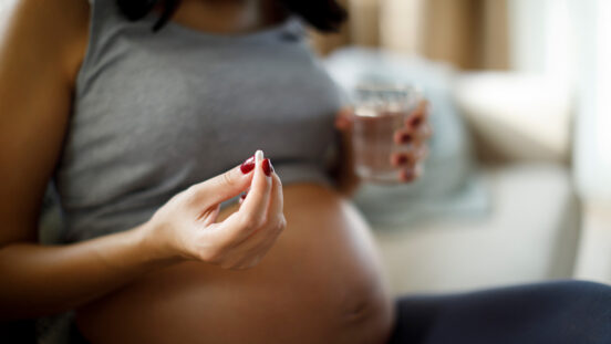 Pregnant woman taking pill at home