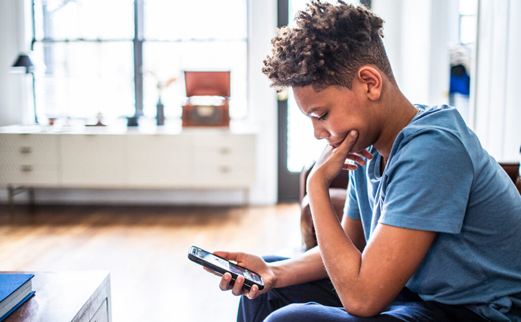 Teenage boy using smartphone in residential living room