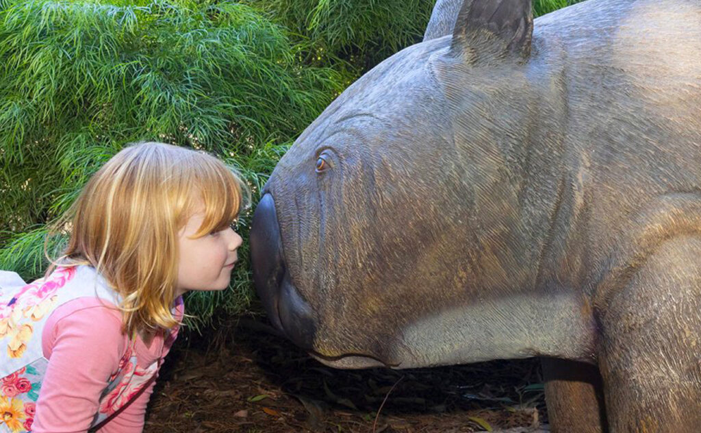 small child nuzzles giant wombat statue at Australian National Botanic Gardens MEGAfauna display