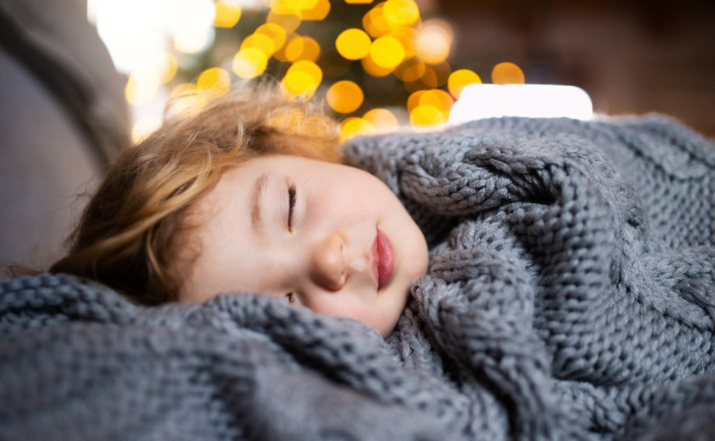 Toddler sleeping peacefully wrapped in a big grey blanket