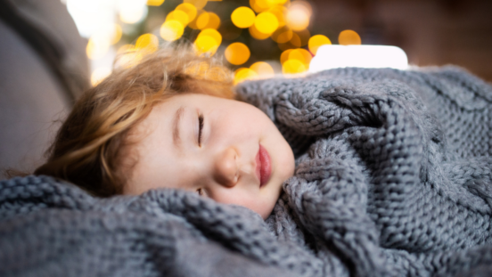 Toddler sleeping peacefully wrapped in a big grey blanket