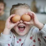 Girl holding two eggs over her eyes