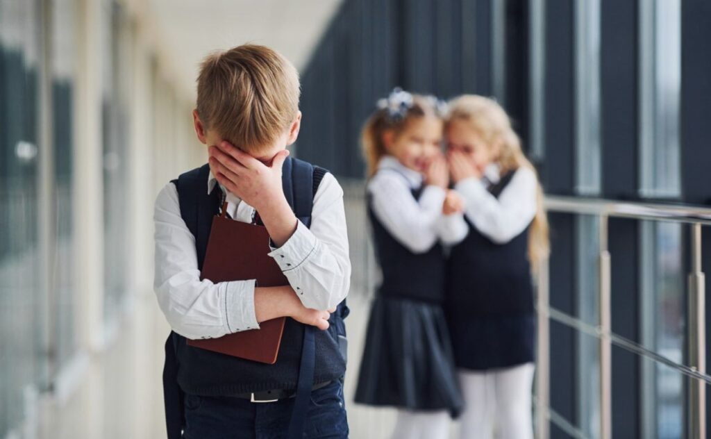 Boy feeling bullied by two girls at school. 