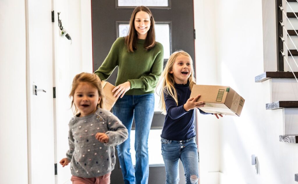 Mum and daughters bringing delivery package into home