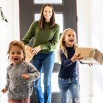 Mum and daughters bringing delivery package into home