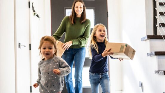 Mum and daughters bringing delivery package into home