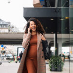 Happy female entrepreneur talking on smart phone while walking in city