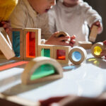 Little kids playing with colourful wooden building blocks on the table - stock photo