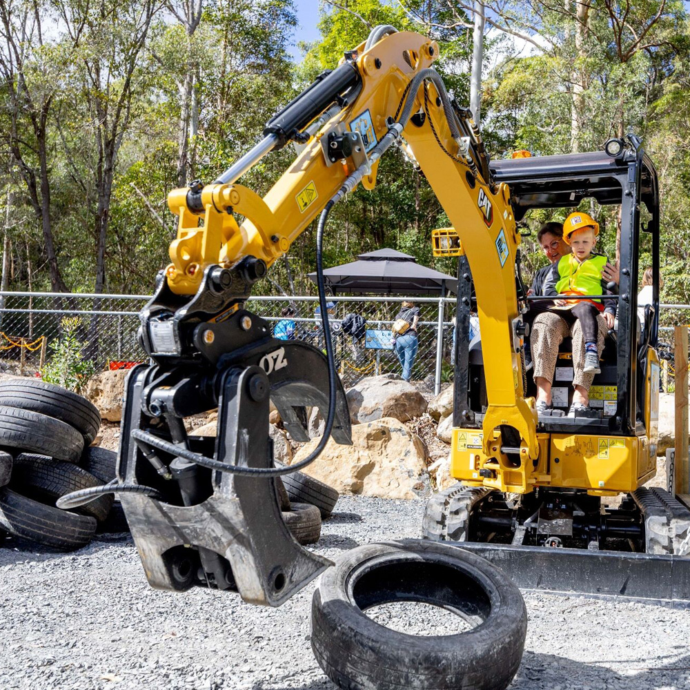 Small child and mother operating heavy digging machinery at Mt Tambourine Dig It