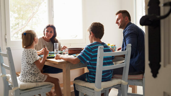 Family At Home In Eating Meal Together