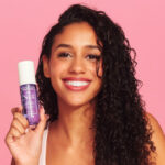 curly haired model holding up fragrance