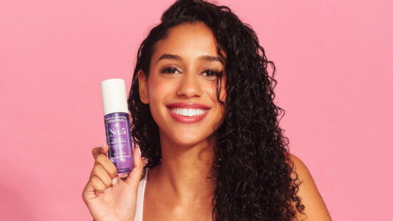 curly haired model holding up fragrance