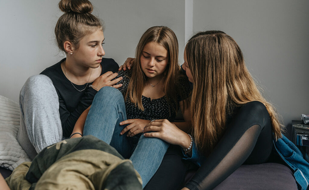 Girlfriends consoling sad teenage girl - stock photo